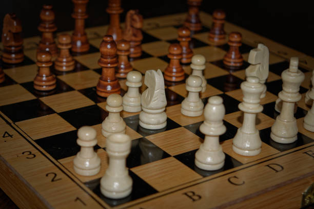 istock Wooden material chess board and chess pieces in low light 982611120