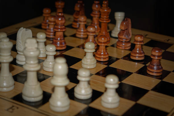 istock Wooden material chess board and chess pieces in low light 982614148