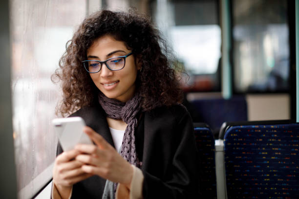 sonriente mujer joven viajando en bus y utilizando el teléfono inteligente - pasajero fotos fotografías e imágenes de stock