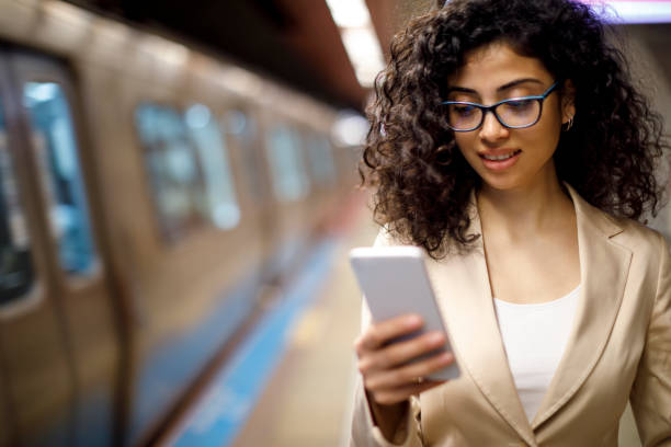 istock Young businesswoman standing on the subway station and using her mobile phone while waiting for the train 982639122