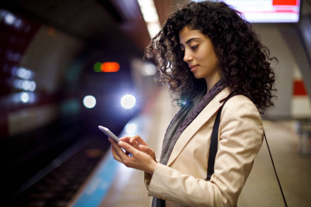 istock Young businesswoman standing on the subway station and using her mobile phone while waiting for the train 982639532
