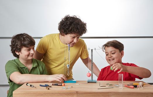 Three kids are doing physics experiments about simple machines