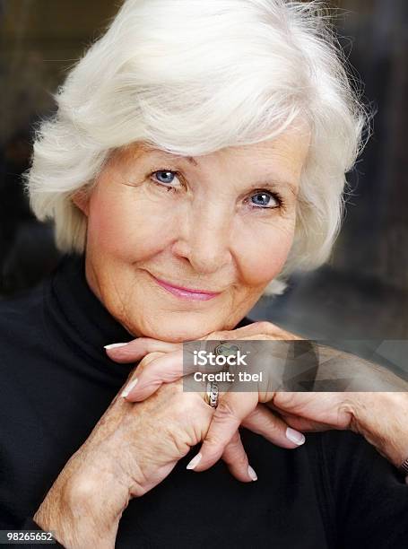 Portrait Of A Smiling Old Woman Resting Face On Hands Stock Photo - Download Image Now