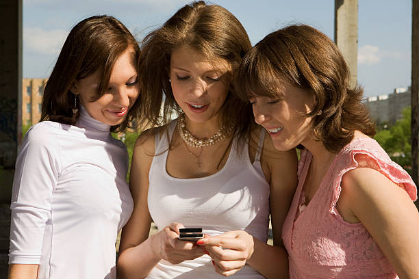 Retrato de três lindas Meninas Jogando com Telefone Móvel - fotografia de stock
