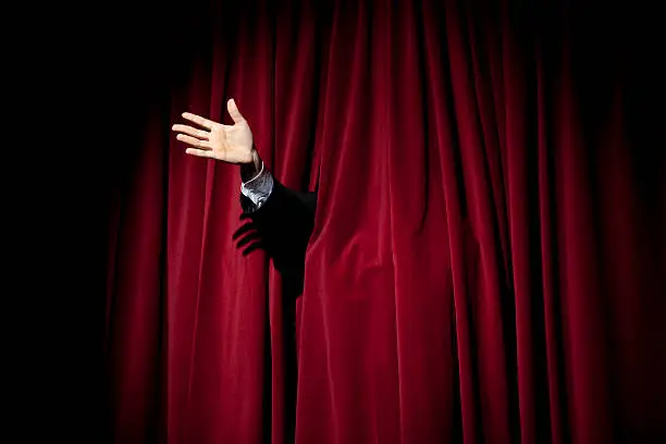 Photo of Hand through red curtain