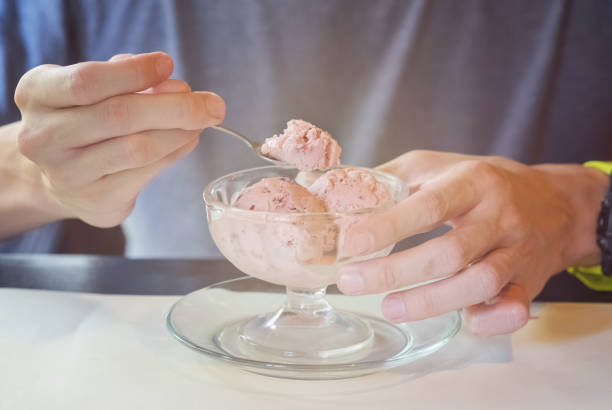 man eating red bean ice-cream man's hand scooping red bean ice-cream from a glass bowl red bean dessert stock pictures, royalty-free photos & images