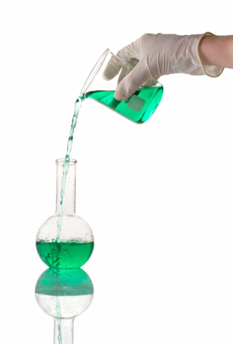 The experimenter's gloved hands flow the chemical from one glass to anothe