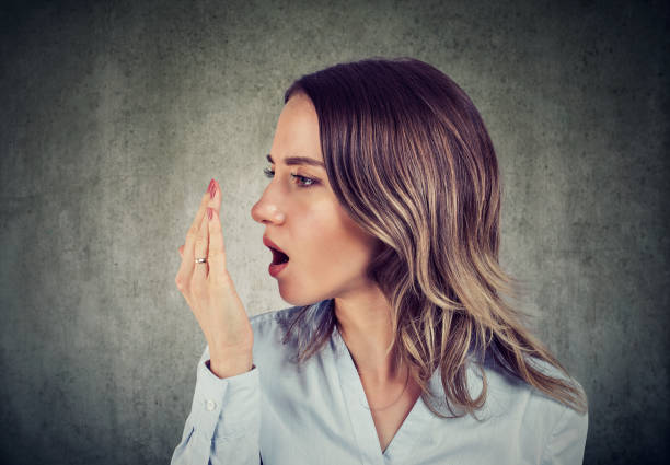 Woman checking her breath with hand.