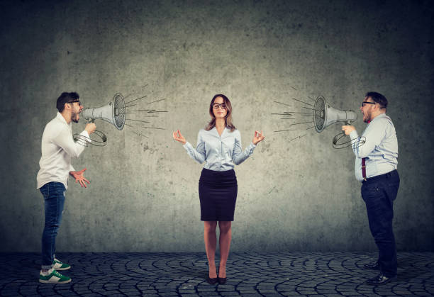 meditating business woman paying no attention to angry men screaming at her in megaphone - yoga meditating business group of people imagens e fotografias de stock