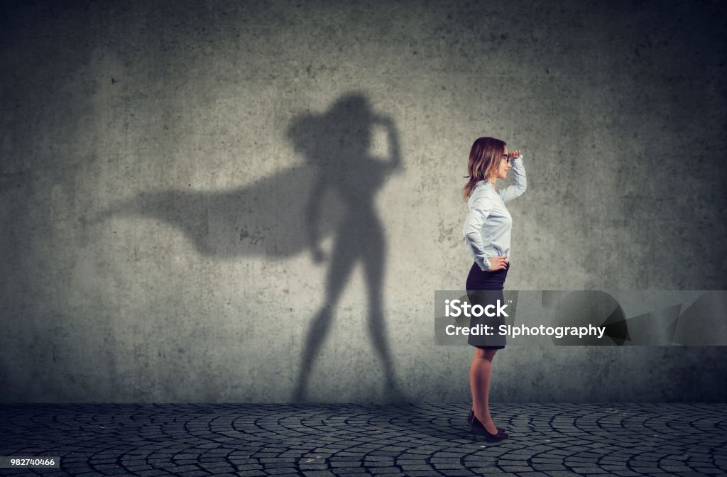 Brave woman posing as super hero Side view of a business woman imagining to be a super hero looking aspired. Women Stock Photo