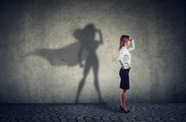 Brave woman posing as super hero Side view of a business woman imagining to be a super hero looking aspired. shadow work stock pictures, royalty-free photos & images
