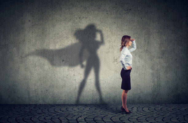 Brave woman posing as super hero Side view of a business woman imagining to be a super hero looking aspired. motivation stock pictures, royalty-free photos & images