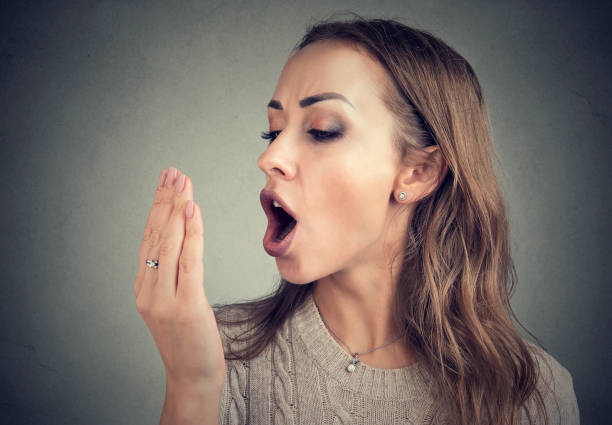 istock Woman checking her breath with hand. 982744870