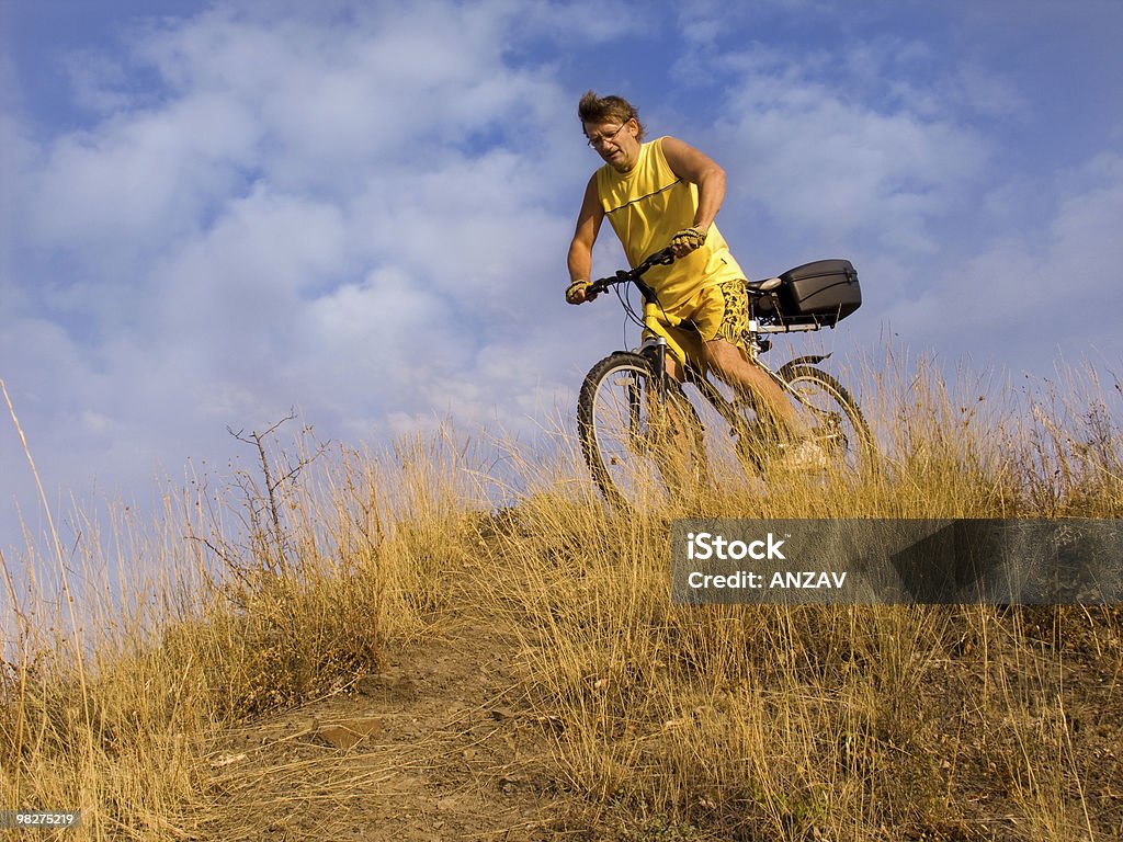 The man on a bicycle The man on a bicycle on a background of the cloudy sky Activity Stock Photo