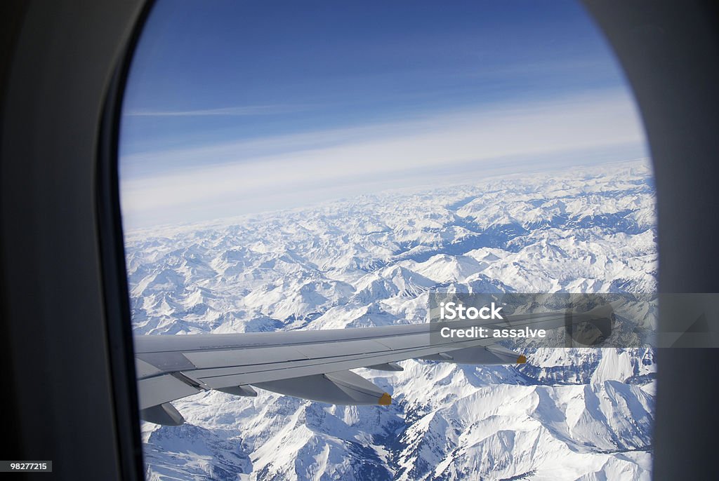 Guardare fuori dalla finestra in volo sopra le Alpi snowcovered - Foto stock royalty-free di Aeroplano