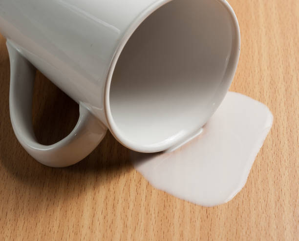 istock Milk spilled from glass on wooden 982773608