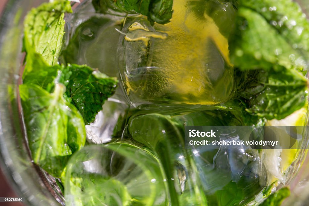 Twigs green mint in mojito with slices lime, ice cubes, straw, macro, texture Twigs green mint in mojito with slices lime, ice cubes, straw, macro, texture, blur Alcohol - Drink Stock Photo
