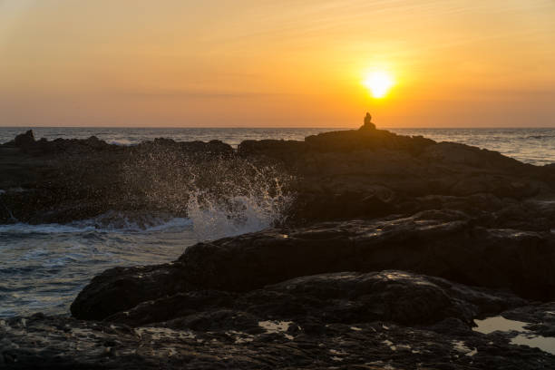 istock Women sitting on rocks at the beach with big waves. 982788606