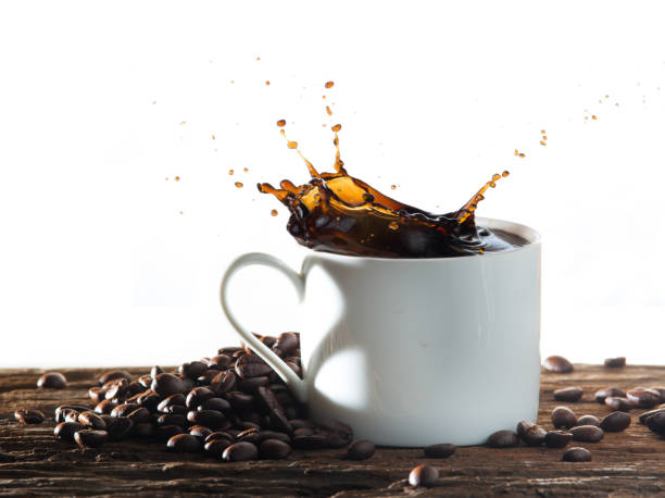 istock Coffee splash with heart shaped handle shadow and coffee beans on wood 982789060