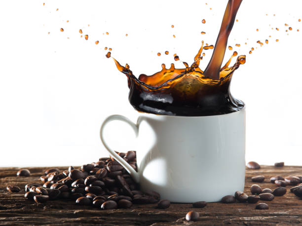 istock Coffee splash with heart shaped handle shadow and coffee beans on wood 982791620
