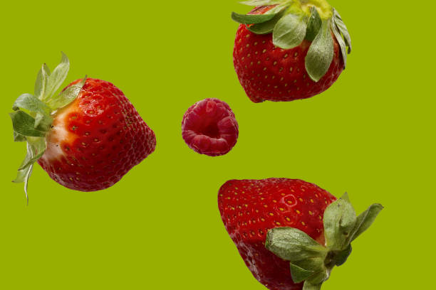 istock high view of three strawberries with a raspberry in the center with green lime background 982796012