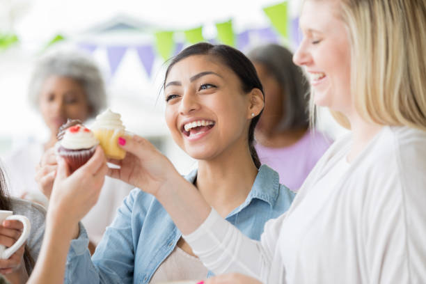istock Young women celebrate by 'toasting' cupcakes during party 982800872