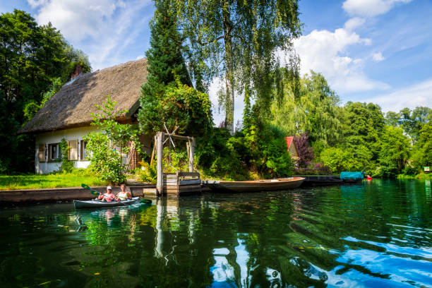 Holiday Spreewald cruise in Lübbenau/Lehde, Germany Lübbenau, Germany - August 02, 2017:Two women kayaking on one of the beautiful channels in the Lübbenau/Lehde area in the beautiful Spreewald, Germany. The Spreewald forest consists of over 200 small canals and waterways of the river Spree which are cutting their way through meadows, calm forest areas and along traditional farmhouses. In 1991 it was designated as biosphere reserve by UNESCO. spreewald stock pictures, royalty-free photos & images