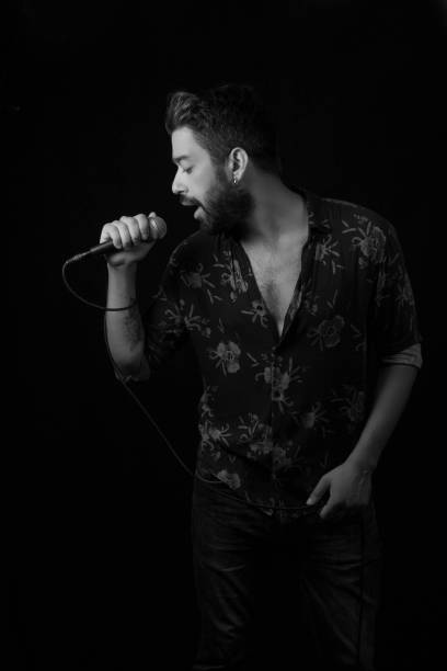 istock Man sings song with microphone on black background, black and white 982811360