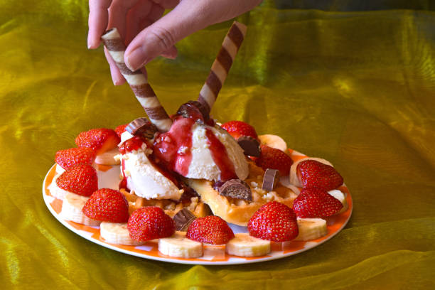 istock Dessert with ice cream decorated with strawberries, bananas, raspberry sauce and waffles 982815404