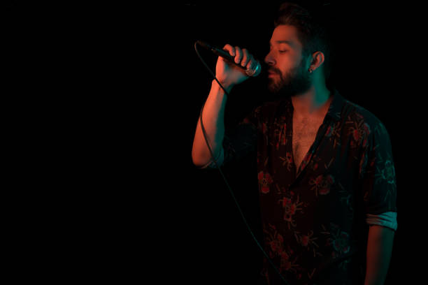istock Man sings song with microphone on black background with gel lighting/ neon lighting 982816318