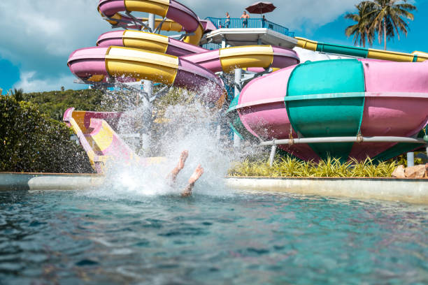 Friends enjoying on slides at water park Male friends having fun on water slides. Men are enjoying summer vacation in pool. They are at water park. sliding down stock pictures, royalty-free photos & images