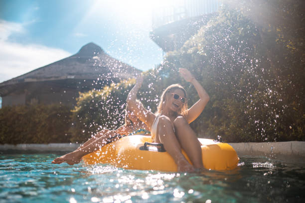 Sisters enjoying on inflatable ring at park Smiling sisters relaxing on yellow inflatable ring at water park. They are floating in swimming pol. They are enjoying summer vacation. excited woman yellow stock pictures, royalty-free photos & images