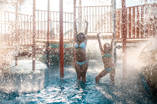 istock Sisters having fun in swimming pool and standing under splashing water 982826894