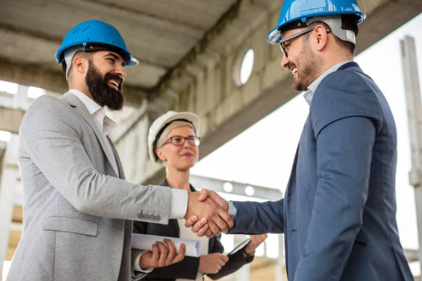 istock Two happy young businessmen shaking hands after a successful meeting on a construction site 982831570