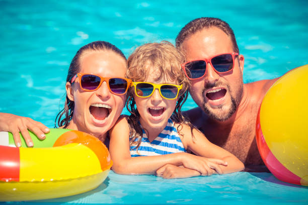 istock Happy family playing in swimming pool 982845602
