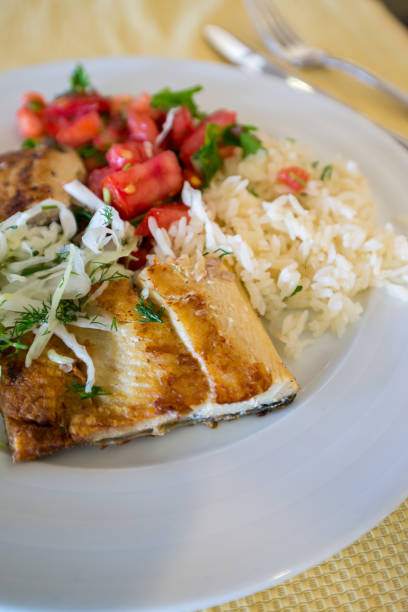 istock fried fish with rice cabbage and tomatoes on plate 982848944