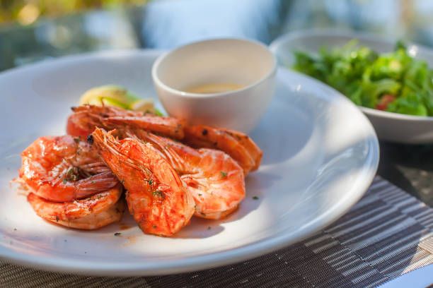 istock Plates with grilled shrimp and salad with tomato behind 982860924