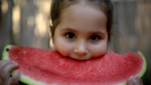 Cute little toddler eating a slice of watermelon