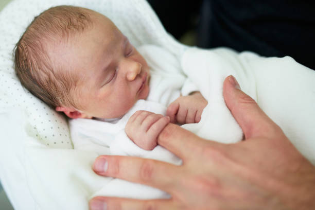 istock Newborn baby sleeping and holding father's finger 982891790