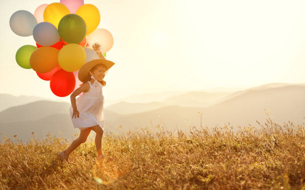 istock happy child with balloons at sunset in summer 982914286