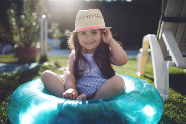 istock Gorgeous child in a swimming ring looking at camera while sitting by the pool 982914302