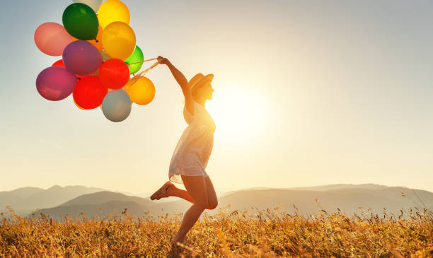 mujer feliz con globos al atardecer en verano - jumping freedom women beach fotografías e imágenes de stock