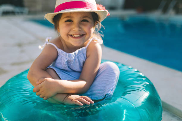 istock Cute smiling girl sitting in a inflatable ring by the pool 982918736