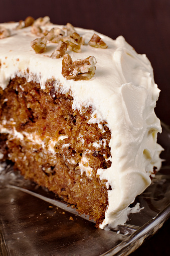 Homemade carrot cake made with carrots, walnuts, cinnamon, iced with cream cheese. Sweet dessert for kids. High angle view.