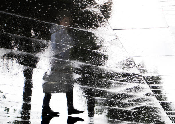 istock Person blurry reflection silhouette on a rainy street 982972744