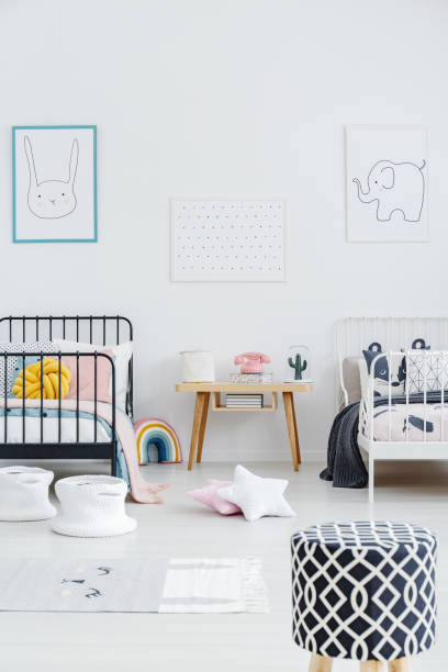 istock Patterned stool in bright kids bedroom interior with posters above black and white bed. Real photo 982989114
