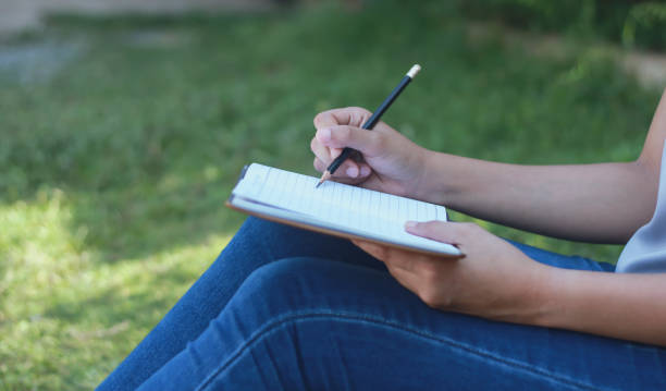 istock woman sitting at lawn taking notes in notebook. lifestyle concept 983079188