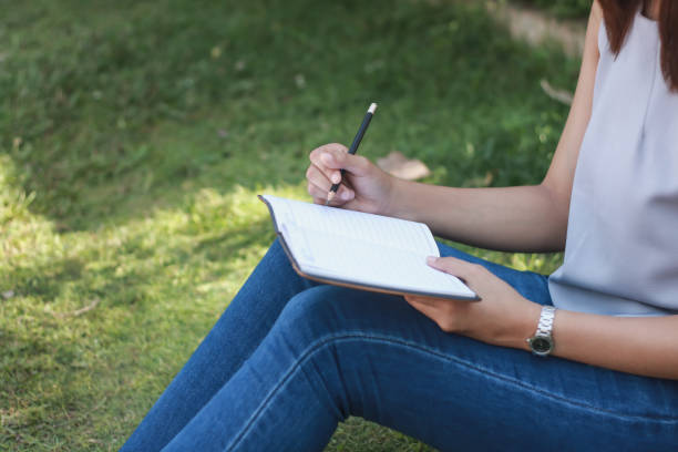 istock woman sitting at lawn taking notes in notebook. lifestyle concept 983079554