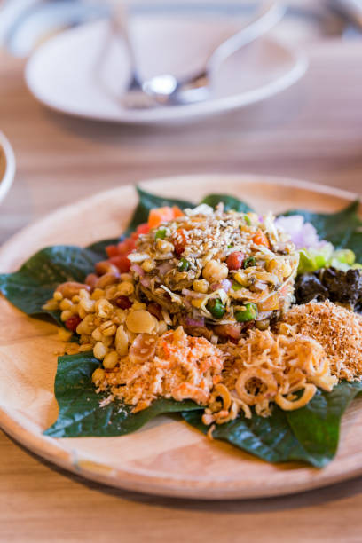 istock Lahpet is Burmese Tea Leaf Salad served with deep fried garlic, peanut, white sesame, dried shrimp, ginger and roasted coconut. 983101904