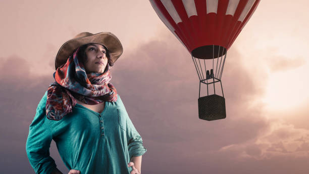 istock Young woman looking toward a hot air balloon 983112172